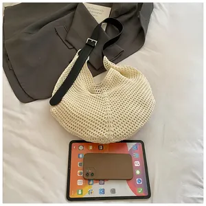 Top-down view of woven hollow tote with adjustable black leather strap on a bed