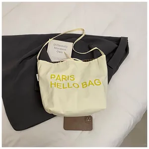 Detailed view of the off-white canvas tote bag featuring yellow PARIS HELLO print decoration