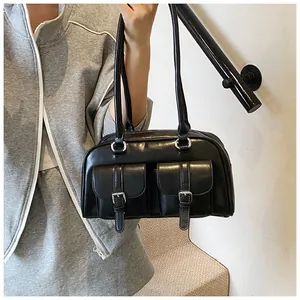 Dettaglio di una borsa a tracolla in pelle nera vintage con tasche a fibbia argento