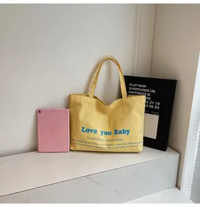 Detail of yellow canvas tote bag with Love you Baby blue printing and motivational text