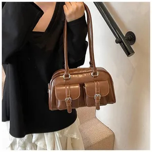 Dettaglio borsa a spalla vintage marrone con tasche a fibbia e cuciture bianche