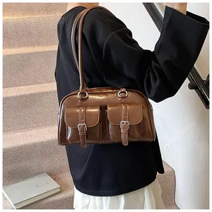Dettaglio di una borsa a spalla in pelle marrone con due tasche frontali e fibbie argento