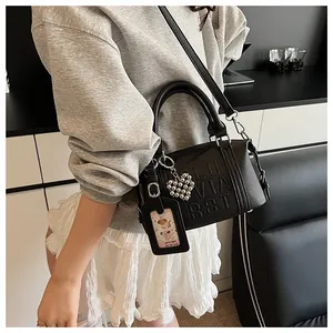 Detail of black pebbled leather pillow bag with embossed letters and heart charm