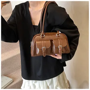 Dettaglio di una borsa a bauletto vintage marrone con finitura lucida e tasche con fibbia