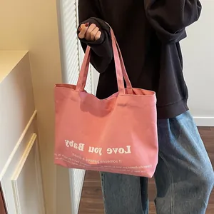 Pink canvas tote bag with Love you Baby print carried by a model in casual style