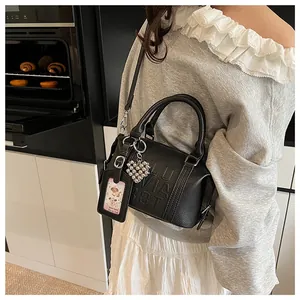 Detail of black pebbled leather Boston bag with embossed logo and heart bead charm