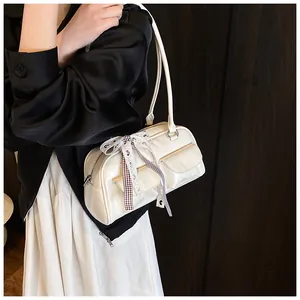 Detail van crème PU-lederen tas met decoratief lint en kleine zakken met voorklep