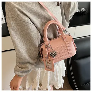 Pink embossed boston bag with heart charm and card holder detail on model shoulder