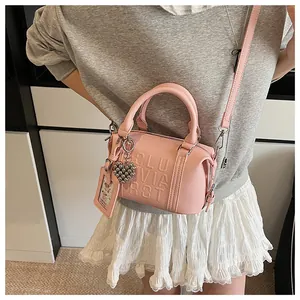Detail of pink embossed mini boston bag with heart charm and litchi grain texture