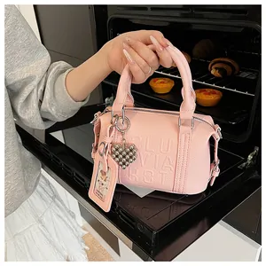 Detail of pink leather pillow bag with embossed letters and cute heart bear pendants