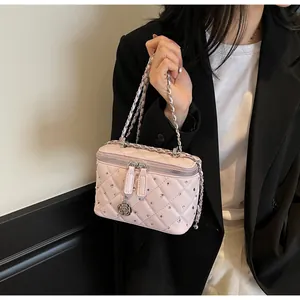 Detail of light pink quilted leather box bag with silver studs and camellia charm