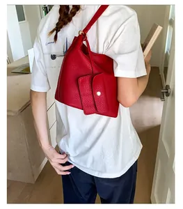 Gros plan du sac seau rouge en cuir texturé litchi avec sa petite pochette assortie
