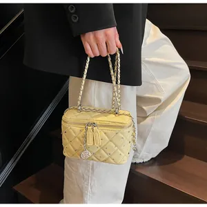 Close-up of yellow quilted vanity bag featuring rhinestone details and flower charm