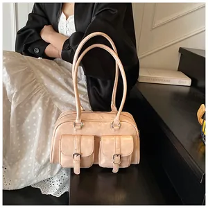 Dettaglio di una borsa hobo crema capiente con fibbie vintage e tasche anteriori