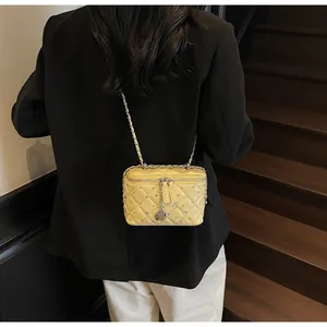 Close-up of yellow quilted chain bag with a metal rose charm on a black blazer