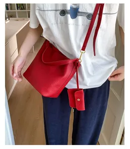 Détail du sac seau rouge en cuir grainé avec bandoulière et petite pochette