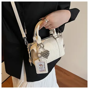 Detail of white leather pillow bag with embossed letters and heart-shaped charm accessory
