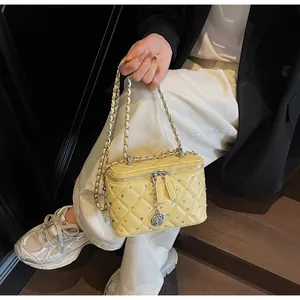 Detail of yellow quilted leather box bag featuring crystal studs and silver camellia charm