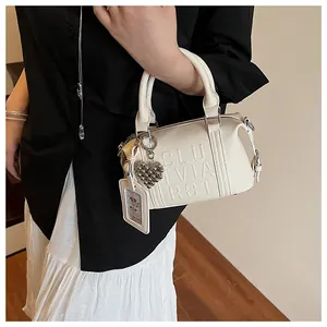 Detail of white lychee pattern pillow bag with embossed letters and heart charm