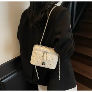 Detail of cream quilted crossbody bag with rhinestone accents and camellia charm
