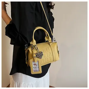 Detailed side view of yellow lychee grain Boston bag with heart charm and shoulder strap