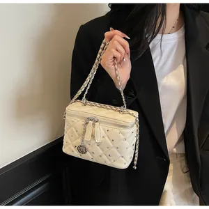Detail of cream quilted bag featuring silver rose charm, studs and metal chain strap