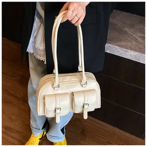 Dettaglio borsa crema con doppie tasche frontali e cinturini decorativi alla moda