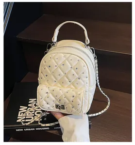 Detailed macro view of cream quilted faux leather mini bag with sparkling rhinestone accents