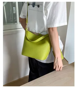 Détail du sac seau en cuir vert citron à texture litchi avec accessoires dorés
