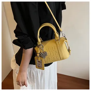 Macro shot of yellow lychee leather boston bag with embossed letters and heart charm