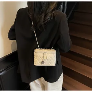Detail of cream quilted crossbody bag with rhinestone accents and rose pendant strap