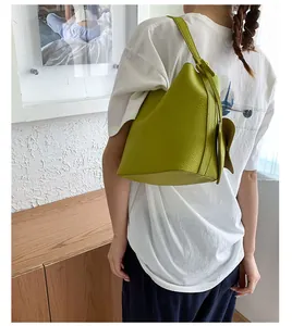 Sac seau vert citron en cuir grainé porté par un mannequin dans un intérieur