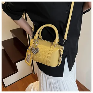 Close-up of yellow embossed letter pillow bag with heart charm and card holder detail