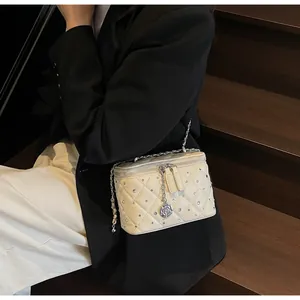 Quilted cream crossbody box bag with silver chain and camellia charm shown on model