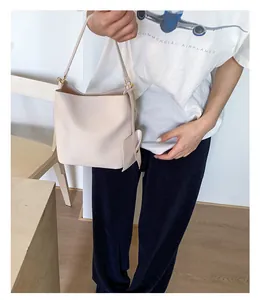 Détail du sac seau en cuir crème avec mini pochette latérale et finitions dorées