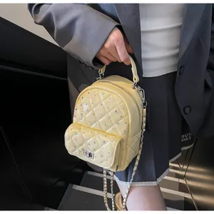 Close-up of a yellow quilted mini backpack with sparkling rhinestones and metal twist lock