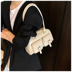 Dettaglio borsa a spalla bianco panna con doppie tasche a patta indossata dal modello