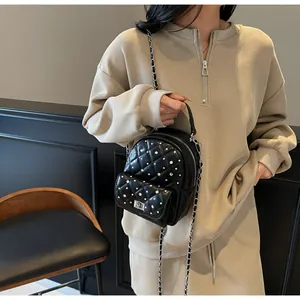 Detail of mini quilted backpack with sparkling rhinestones and silver chain strap
