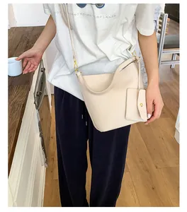 Vue détaillée d'un sac seau crème à texture litchi avec une petite pochette amovible