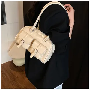Dettaglio della borsa a spalla bianco crema con due tasche frontali e fibbie in metallo