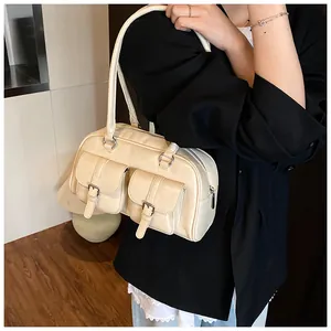 Dettaglio di una borsa a spalla bianco crema con doppie tasche anteriori e fibbie in metallo
