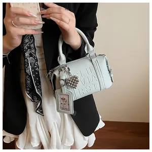 Detail of light blue lychee leather boston bag with embossed letters and heart charm