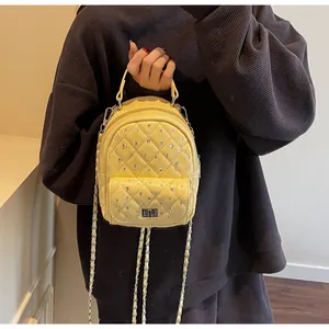Detail of yellow quilted mini backpack with rhinestone studs and silver twist lock