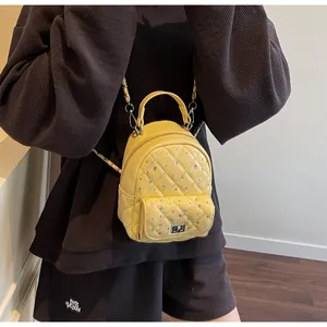 Detail of yellow quilted mini backpack with rhinestones and metal chain strap on model