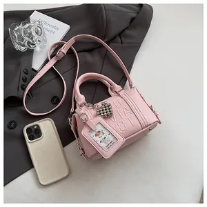 Detail of pink pebbled leather pillow bag with embossed letters and cute dog card holder