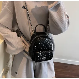 Detail of a mini black backpack featuring quilted diamond stitching and silver rivets