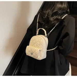 Close-up of quilted mini backpack with rhinestone details and chain straps on model