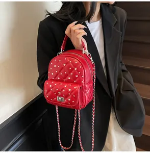 Close-up of a red quilted mini backpack with rhinestones and silver chain strap