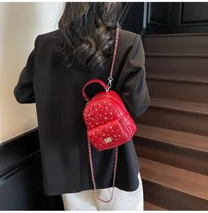 Macro shot of red quilted faux leather mini backpack with sparkling rhinestones and chain strap