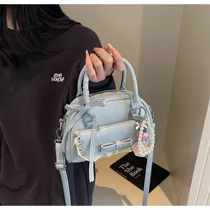 Détail du sac à main bleu clair avec dentelle blanche et pendentif en perles